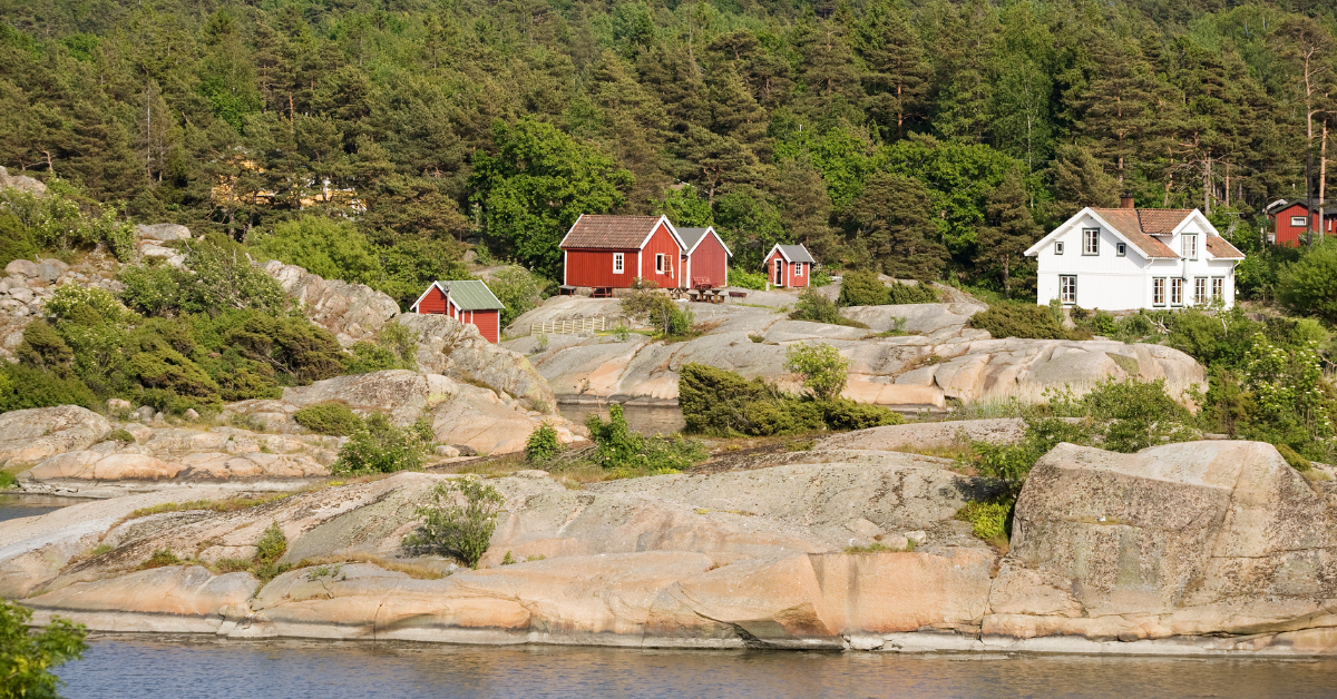 Røde og hvite hytter på svaberg ved sjøen